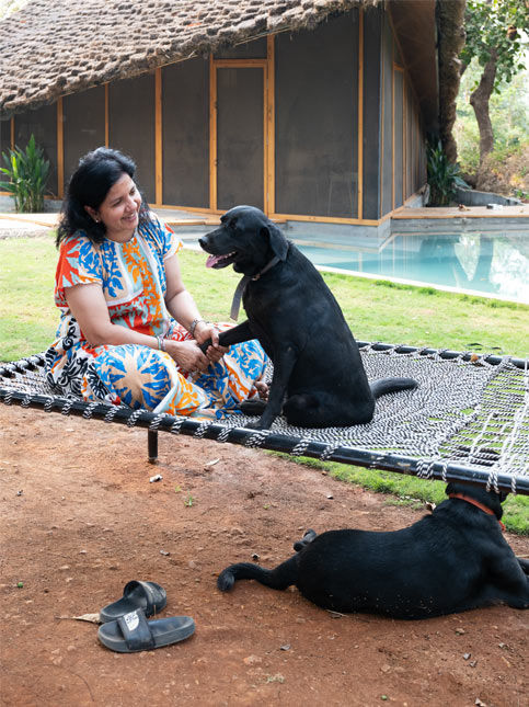Woman with dogs in garden by thatched home – Beautiful Homes
