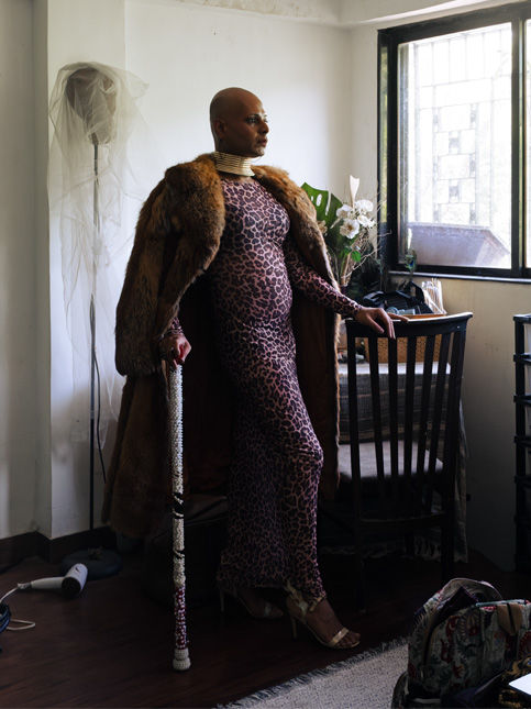 Person in animal print outfit and faux fur coat standing by window – Beautiful Homes