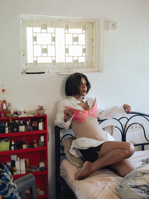 Person sitting on bed with red shelf and white window – Beautiful Homes