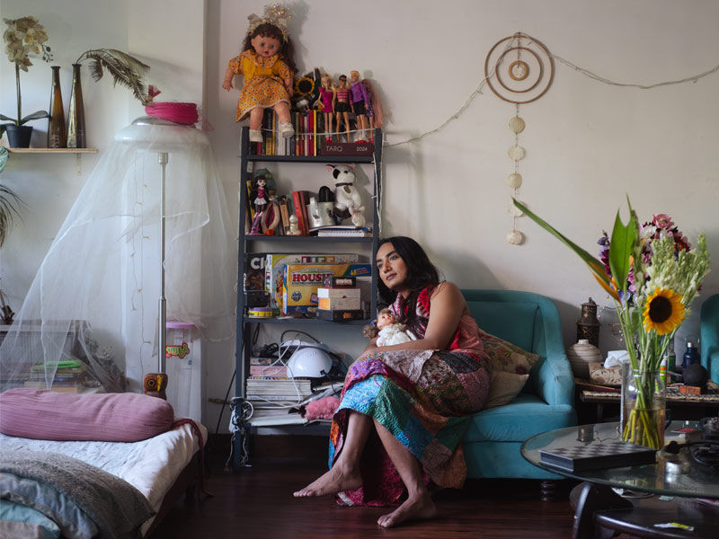 Person sitting on blue sofa surrounded by artistic décor – Beautiful Homes