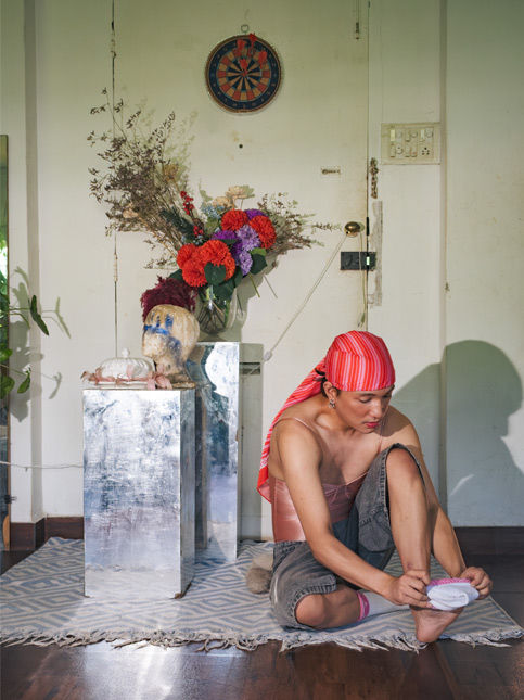 Person wearing a red headwrap sitting next to a floral arrangement – Beautiful Homes