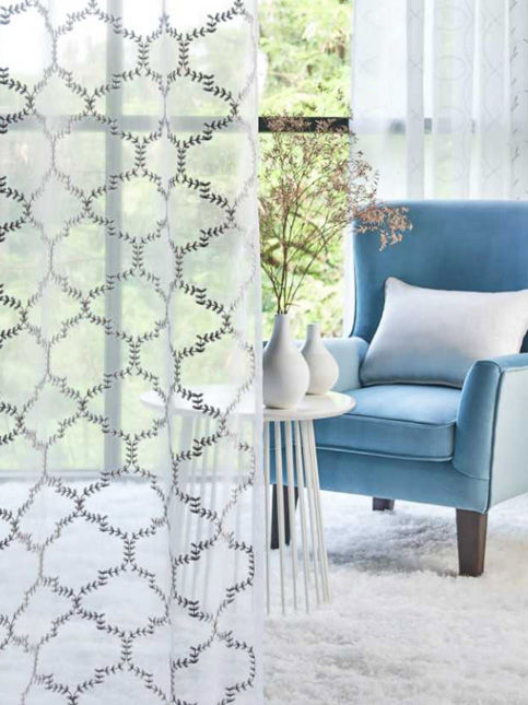 Modern living room with blue wingback chair and sheer embroidered curtains – Beautiful Homes