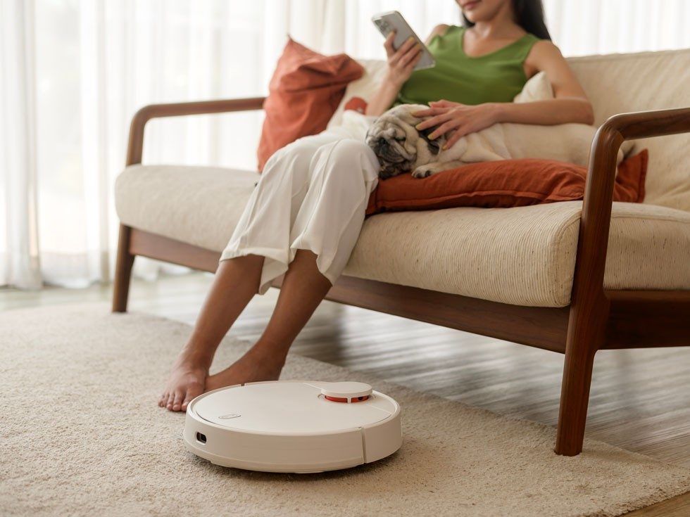 Robotic vacuum cleaner cleaning carpet near sofa with woman and dog – Beautiful Homes