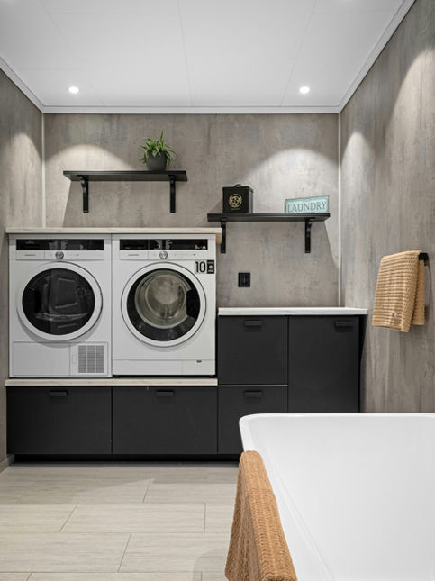 A laundry room featuring a stacked washer and dryer, wooden shelf decor, and a bathtub – Beautiful Homes