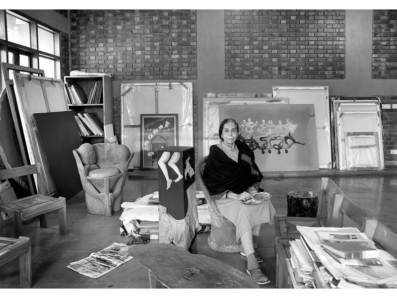 Arpana Caur seated in her art studio surrounded by canvases and paintings – Beautiful Homes