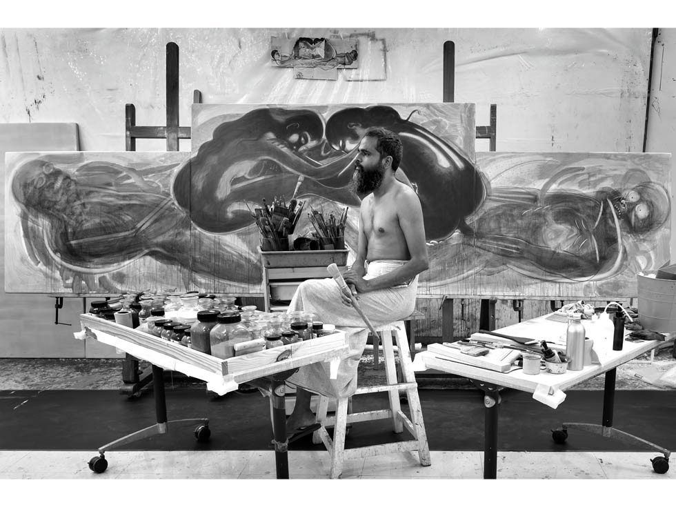 T Venkanna seated before a large-scale painting in his studio – Beautiful Homes