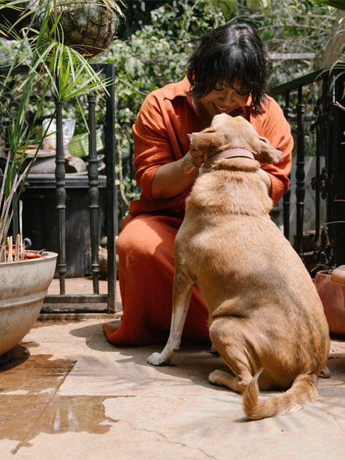 Happy woman wearing orange dress bonding with her dog in patio – Beautiful Homes
