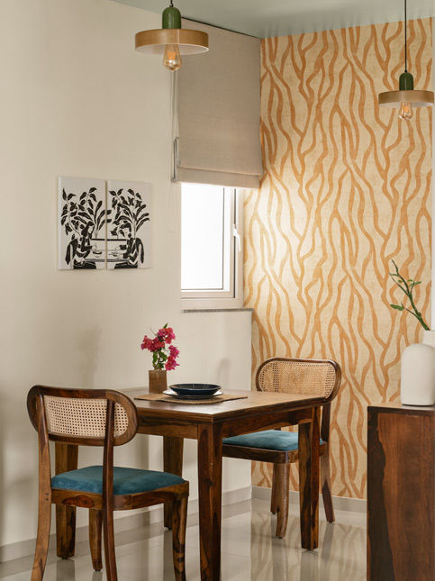 An intimate nook and warm wooden furniture set off the graphic element of the Nilaya Wallpaper – Beautiful Homes