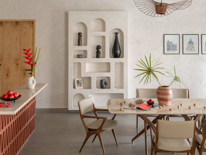 The dining area designed by BASICS Studio features a pendant light sourced from Zeqon and wall paintings by Khushboo Kakkar – Beautiful Homes
