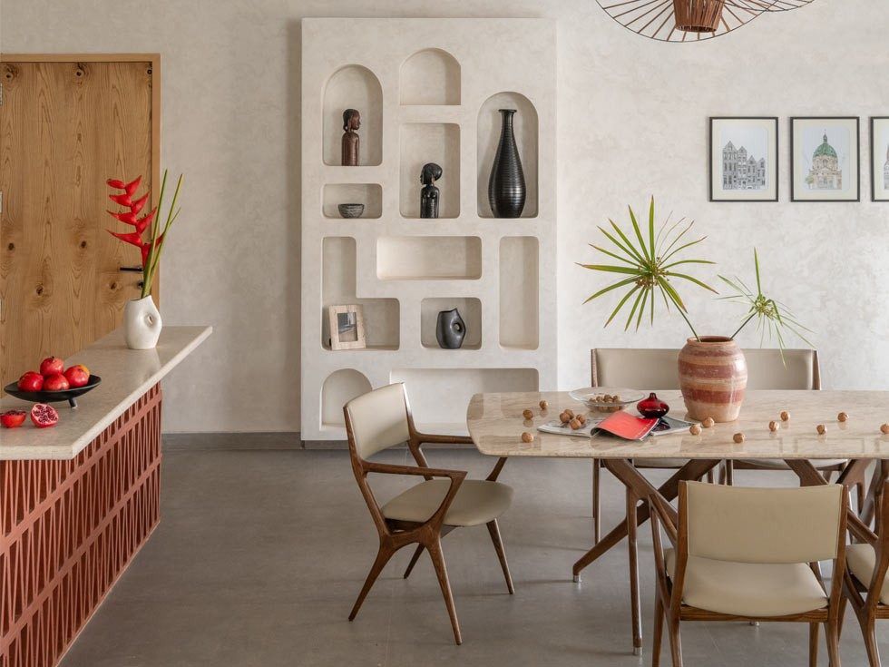The dining area designed by BASICS Studio features a pendant light sourced from Zeqon and wall paintings by Khushboo Kakkar – Beautiful Homes