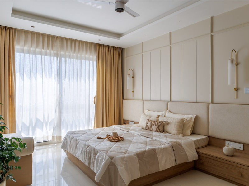Beige master bedroom with grid-panelled headboard and brass accents - Beautiful Homes