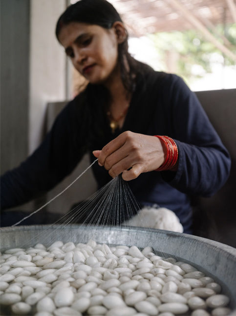 Artisan drawing silk fibres from cocoons by hand - Beautiful Homes