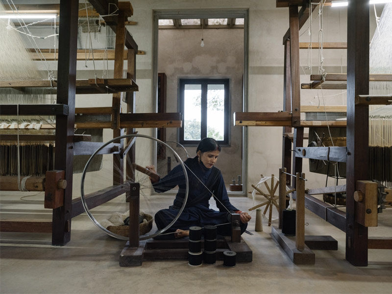 Artisan spinning silk fibres on traditional spinning wheel - Beautiful Homes