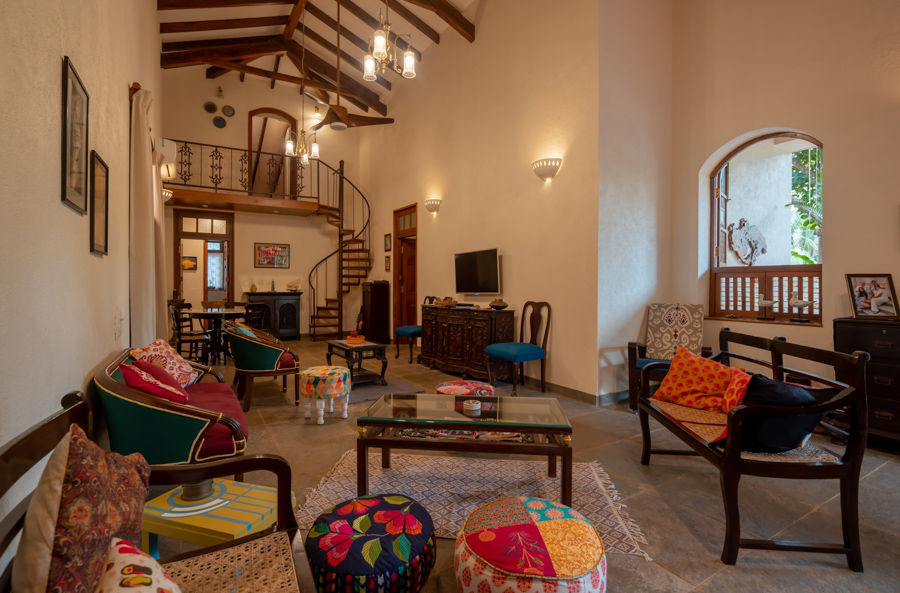 Ethnic family room with colourful cushions and ottoman, wooden ceiling and twisted staircase