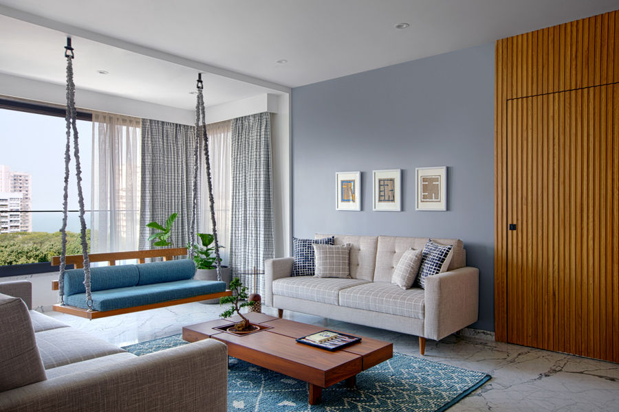 Nautical family room design with wood door and coffee table, swing in front of big window, off-white couches
