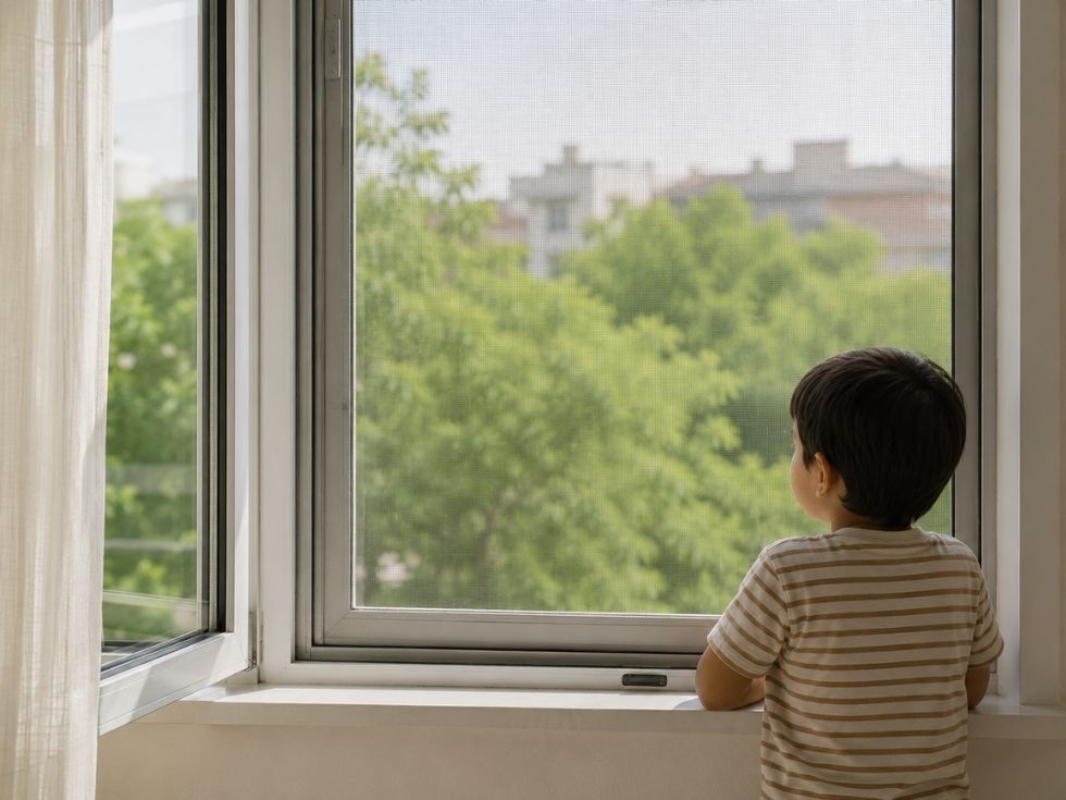 Child looking through a uPVC window fitted with a mosquito screen that allows airflow while maintaining safety and visibility - Beautiful Homes