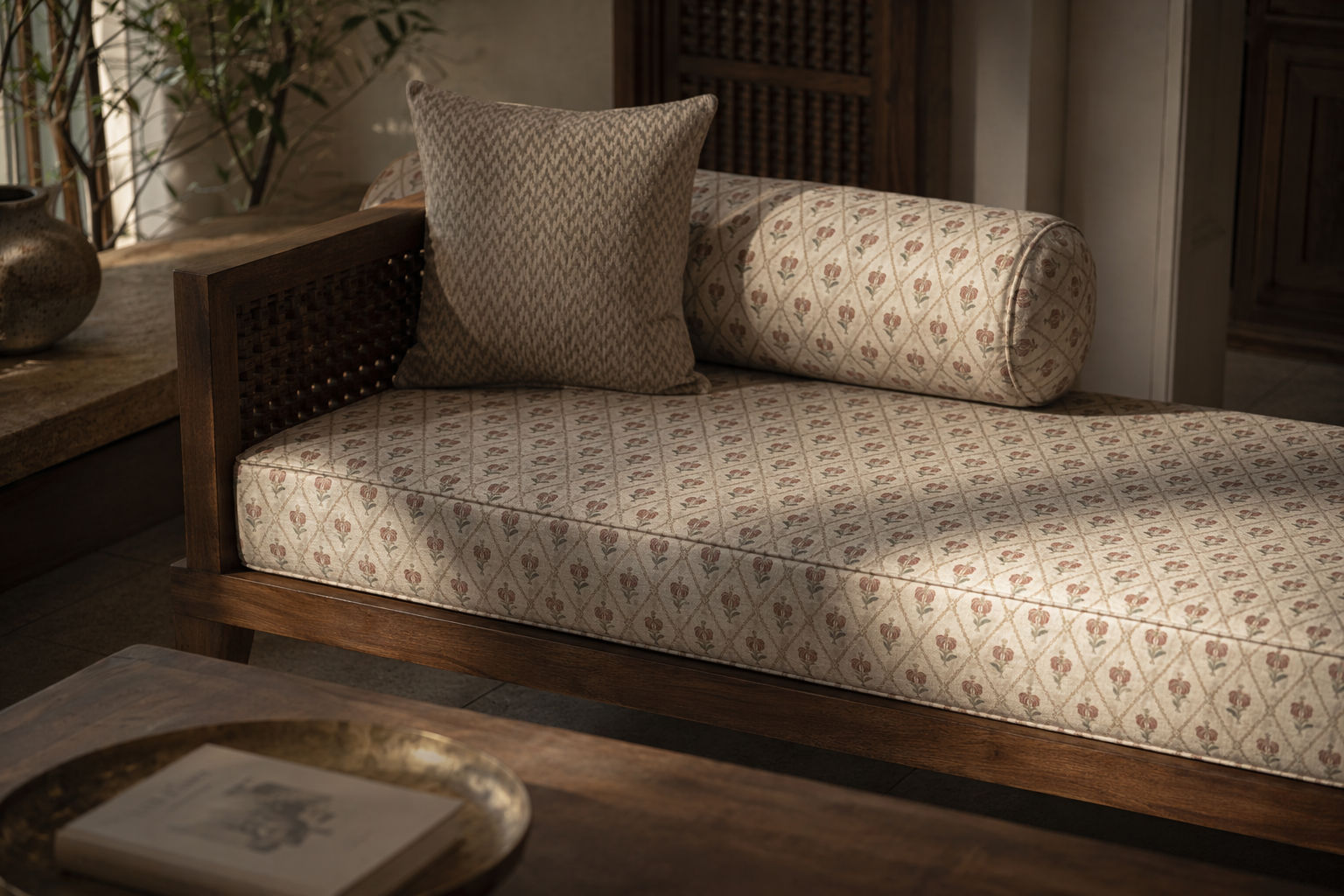 Dark wood daybed with a woven cane side detail and cream upholstered seat in a diamond floral pattern - Beautiful Homes