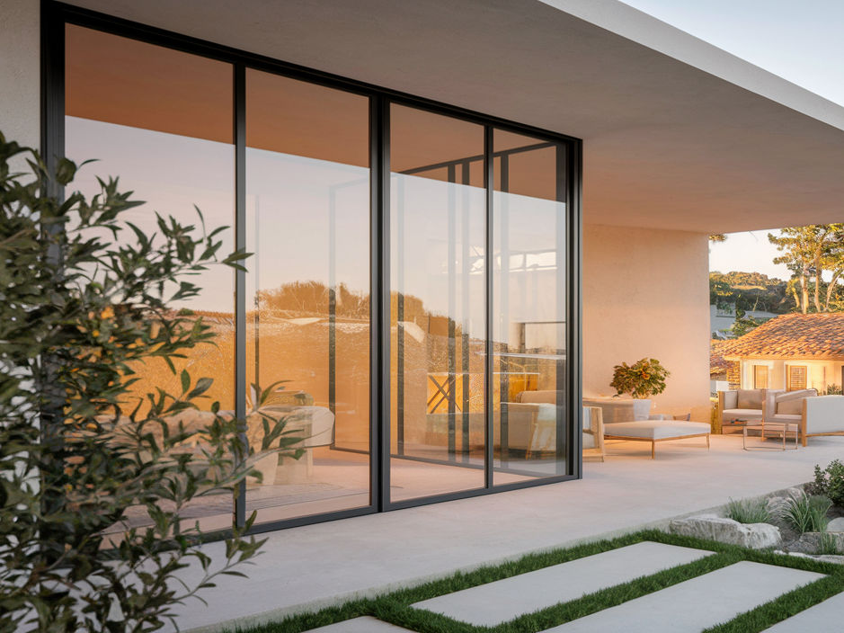 Modern outdoor living space with glass sliding doors, patio furniture, and warm lighting - Beautiful Homes