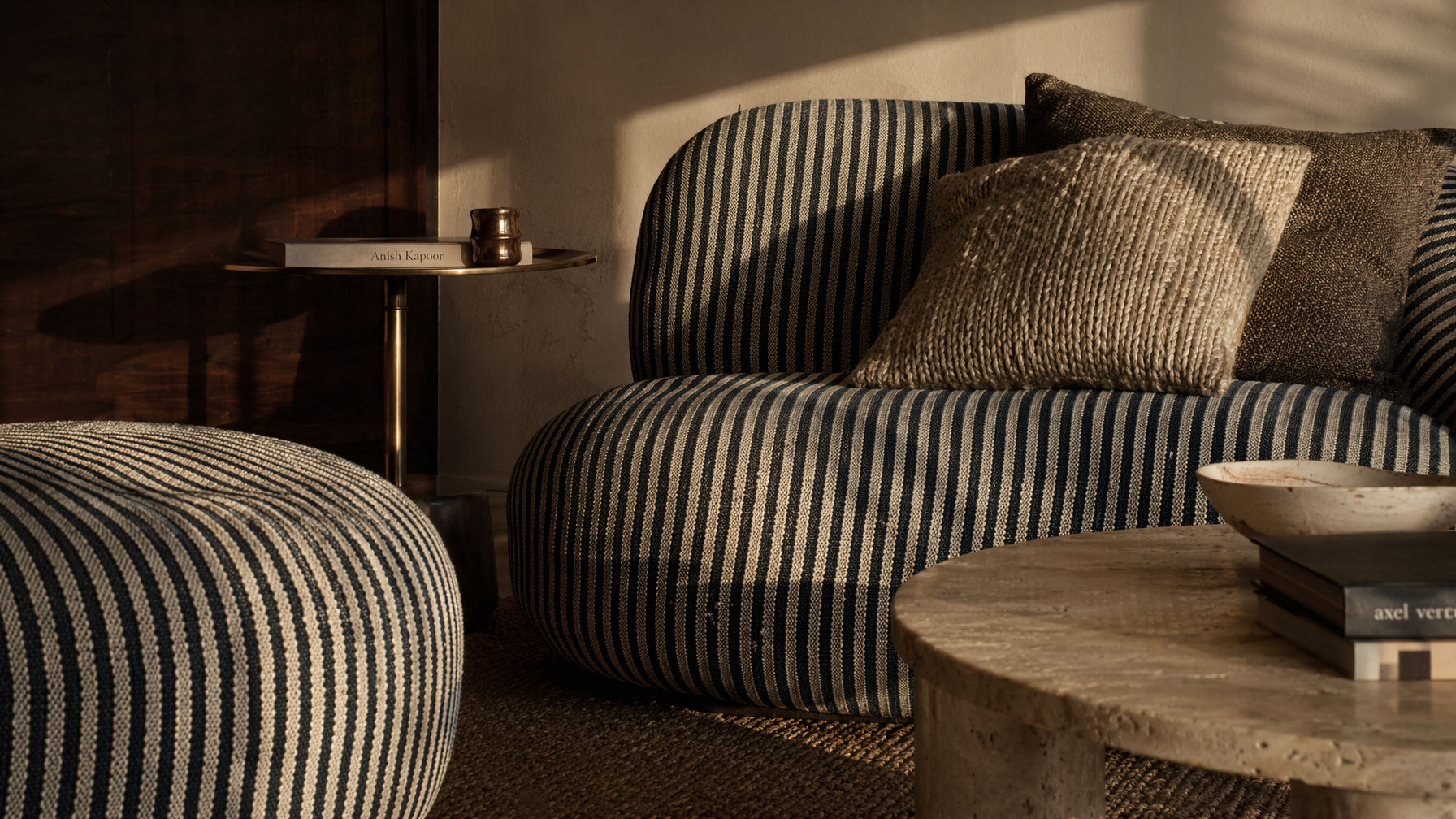 Low-profile sofa furnishing with black and cream striped upholstery, plush layered cushions, and a matching ottoman - Beautiful Homes
