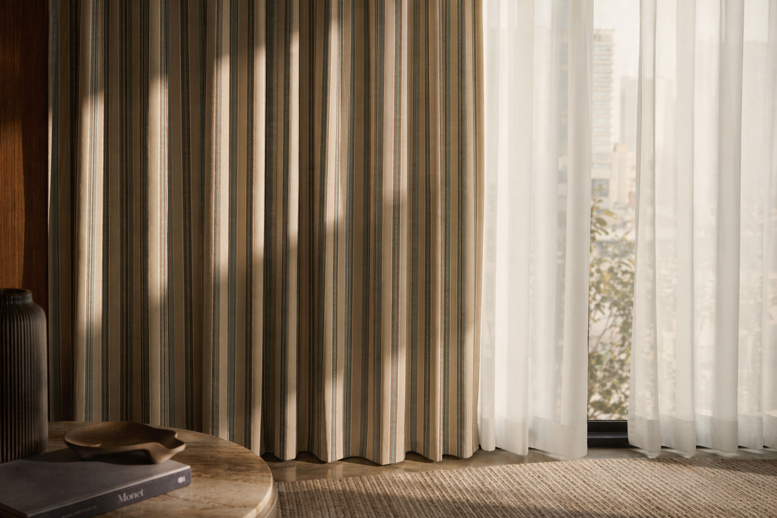 Floor-length curtain furnishing with textured vertical stripes in beige, taupe, brown, and soft teal, paired with airy white sheer drapes - Beautiful Homes