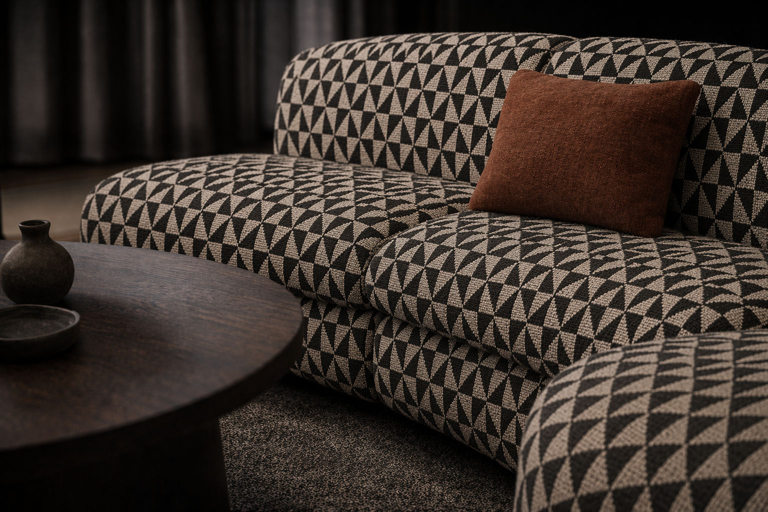 Low-profile modular sofa with black and beige geometric woven upholstery, a curved silhouette, and a rust accent cushion in a refined modern setting - Beautiful Homes