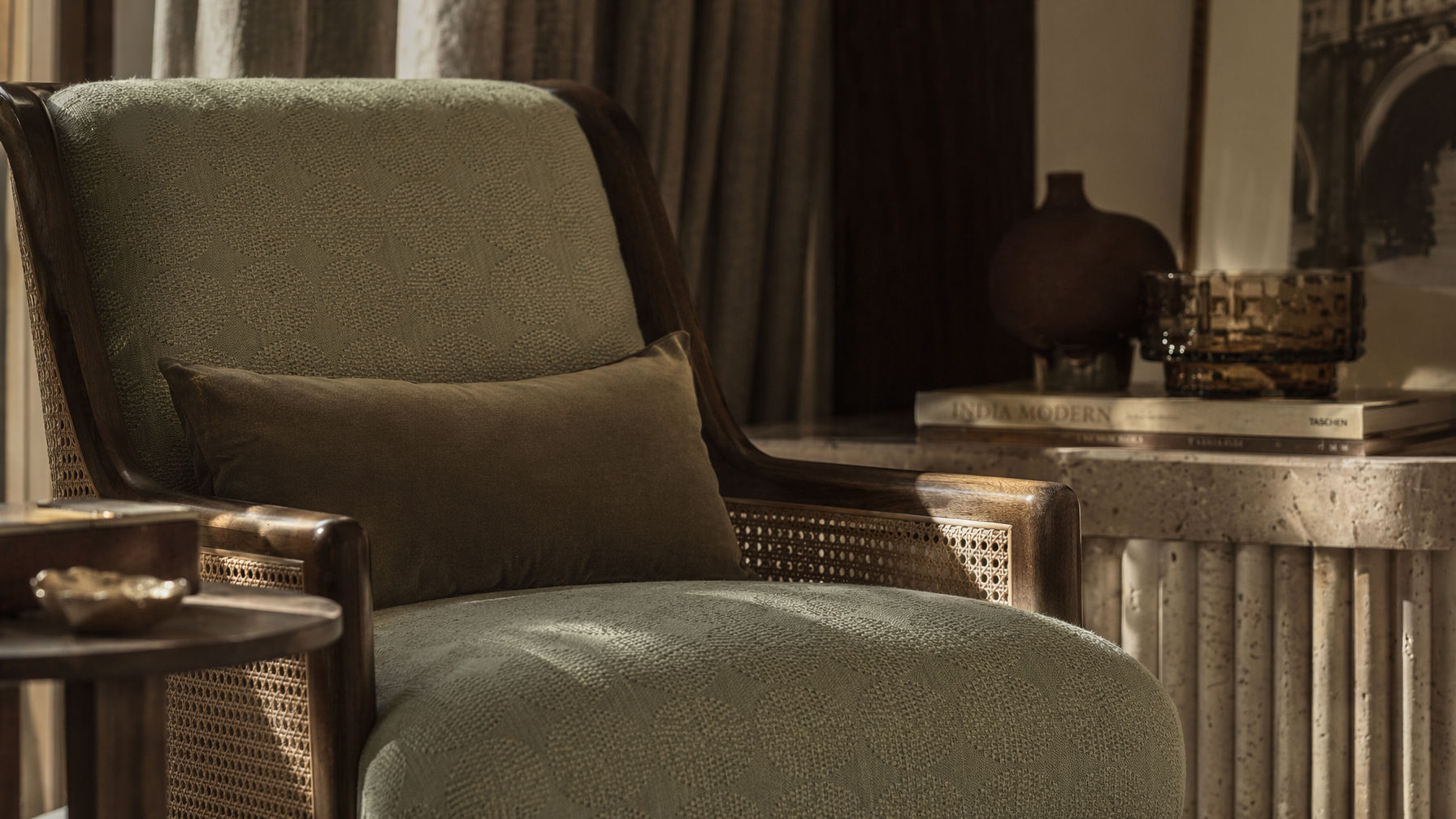 Sofa-style furnishing with a dark wood frame, woven cane side panels, sage textured upholstery, and a contrasting lumbar cushion - Beautiful Homes