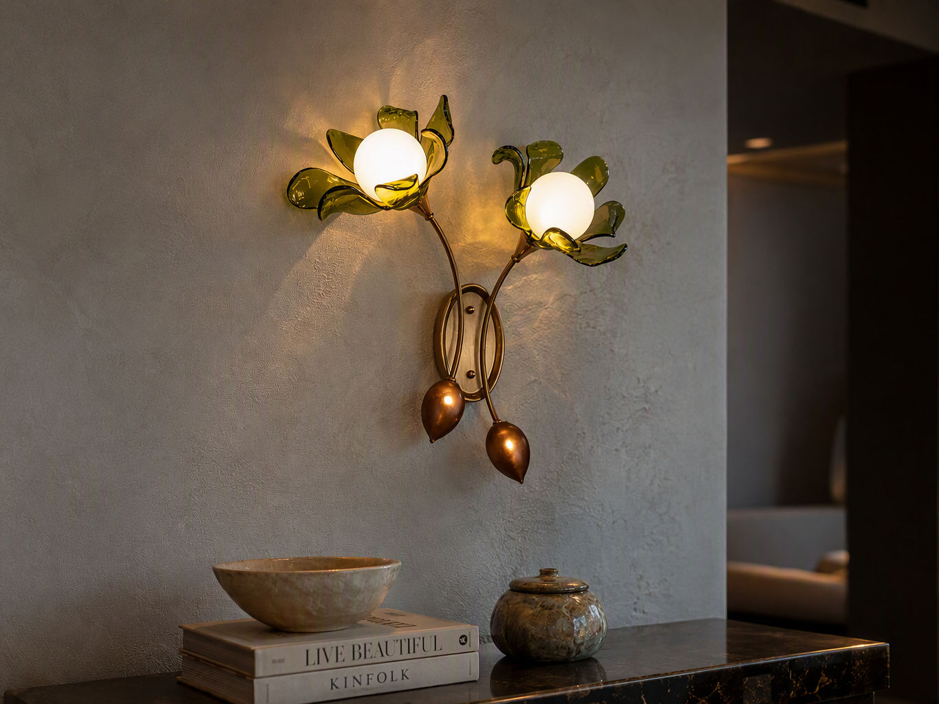 Double wall sconce with antique brass arms, translucent green glass petal shades, frosted globe bulbs, and decorative bud details - Beautiful Homes
