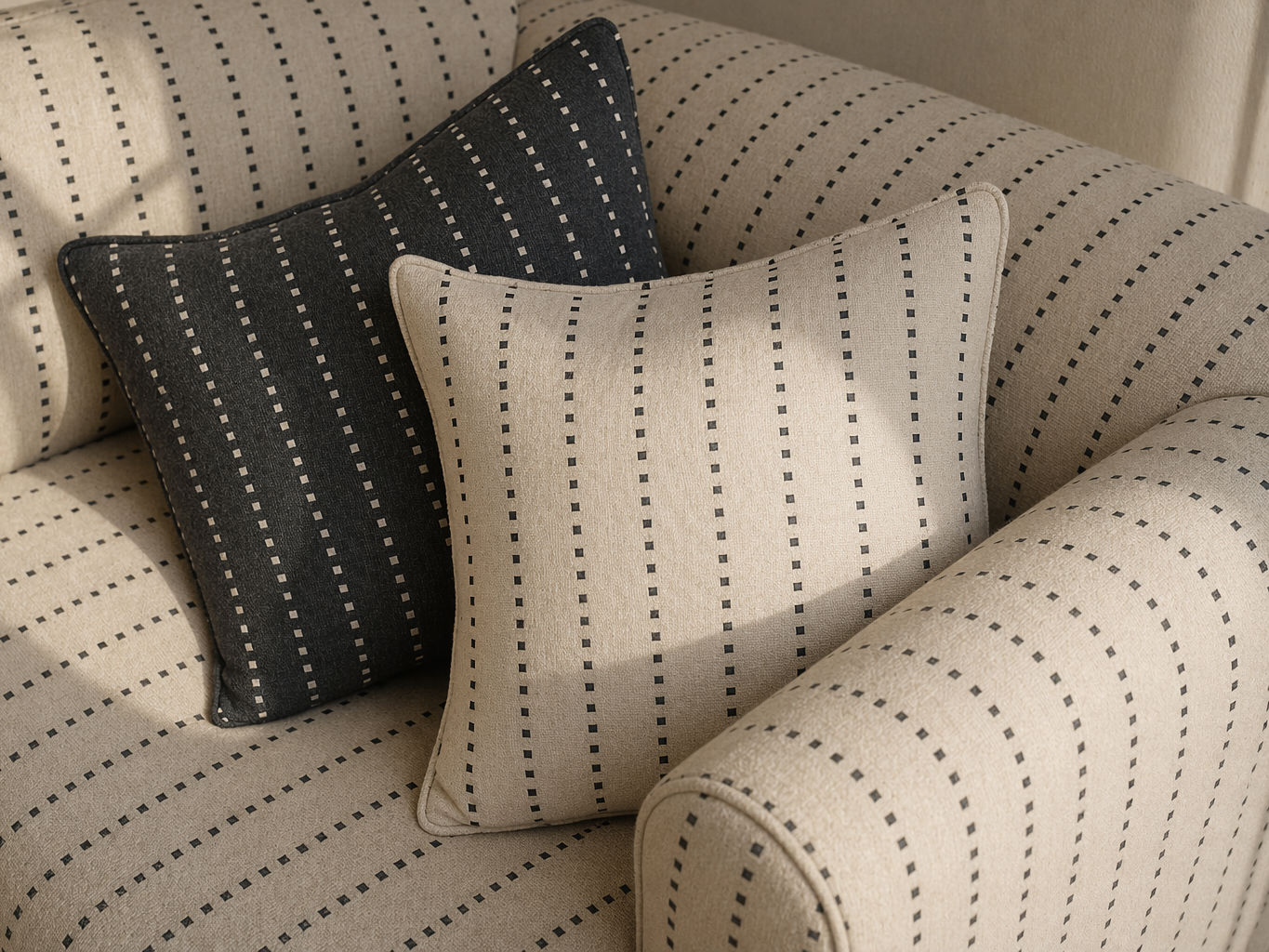 Beige upholstered sofa with subtle dashed stripe fabric, styled with coordinated light and charcoal patterned cushions for a layered contemporary look - Beautiful Homes