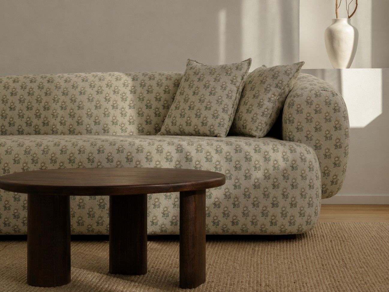 Low-profile curved sofa upholstered in an off-white floral fabric with sage and beige motifs, styled in a warm contemporary interior - Beautiful Homes