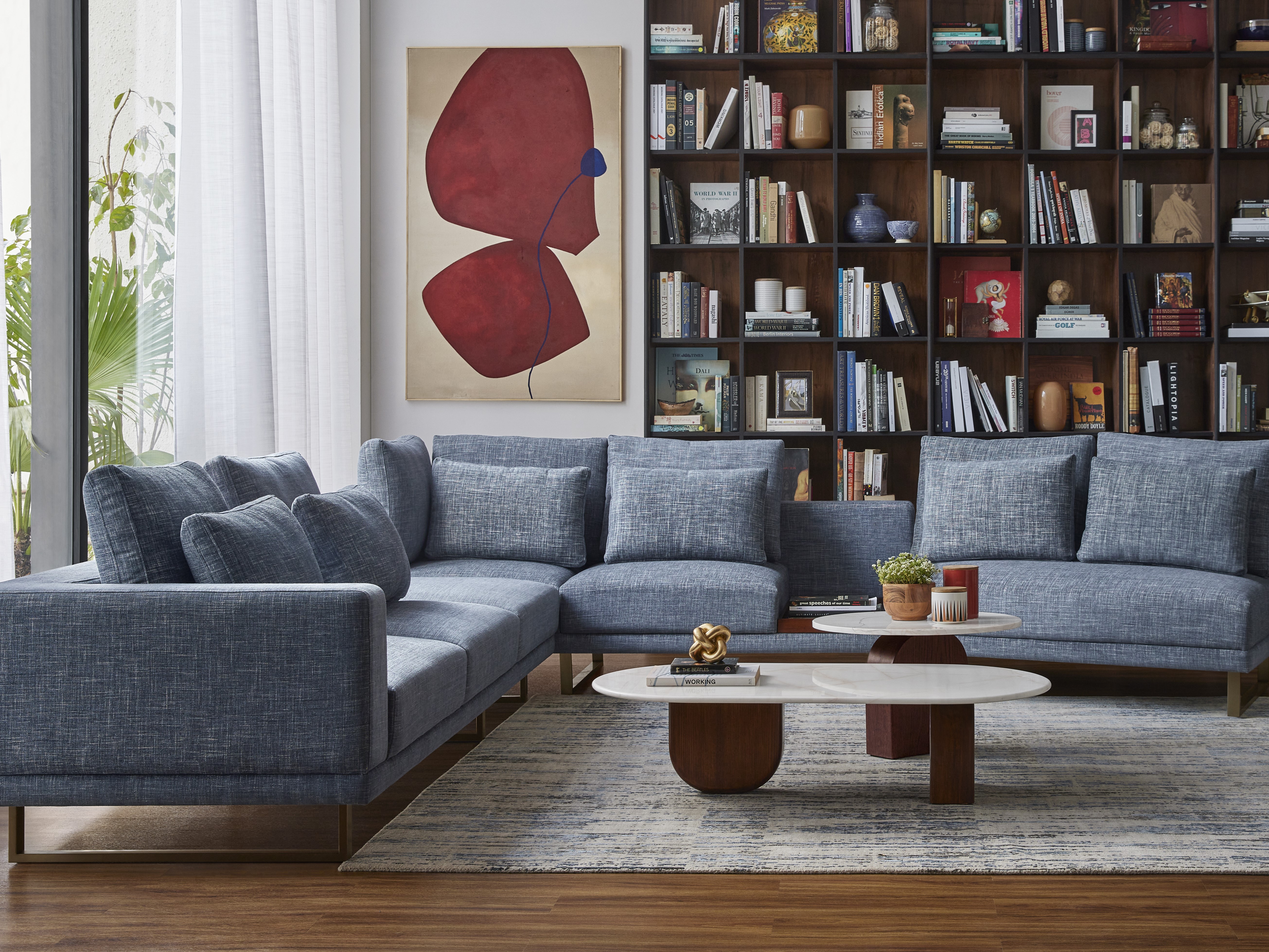 Living room with blue sofa and wooden bookshelf - Beautiful Homes