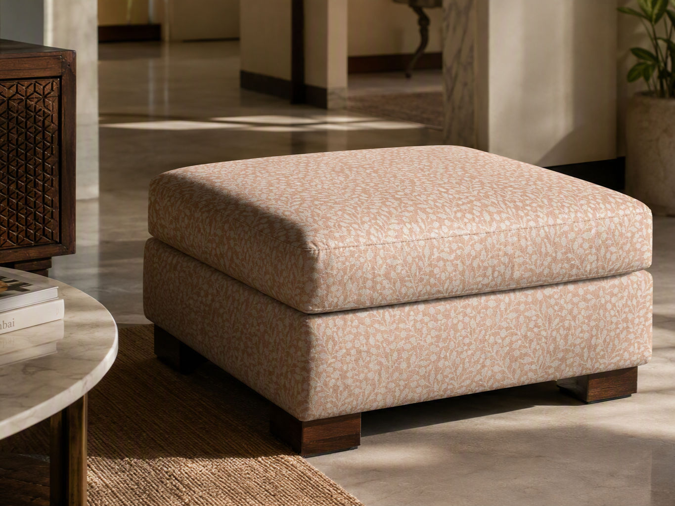Square upholstered ottoman in peach fabric with a delicate white botanical pattern and dark wooden block feet - Beautiful Homes