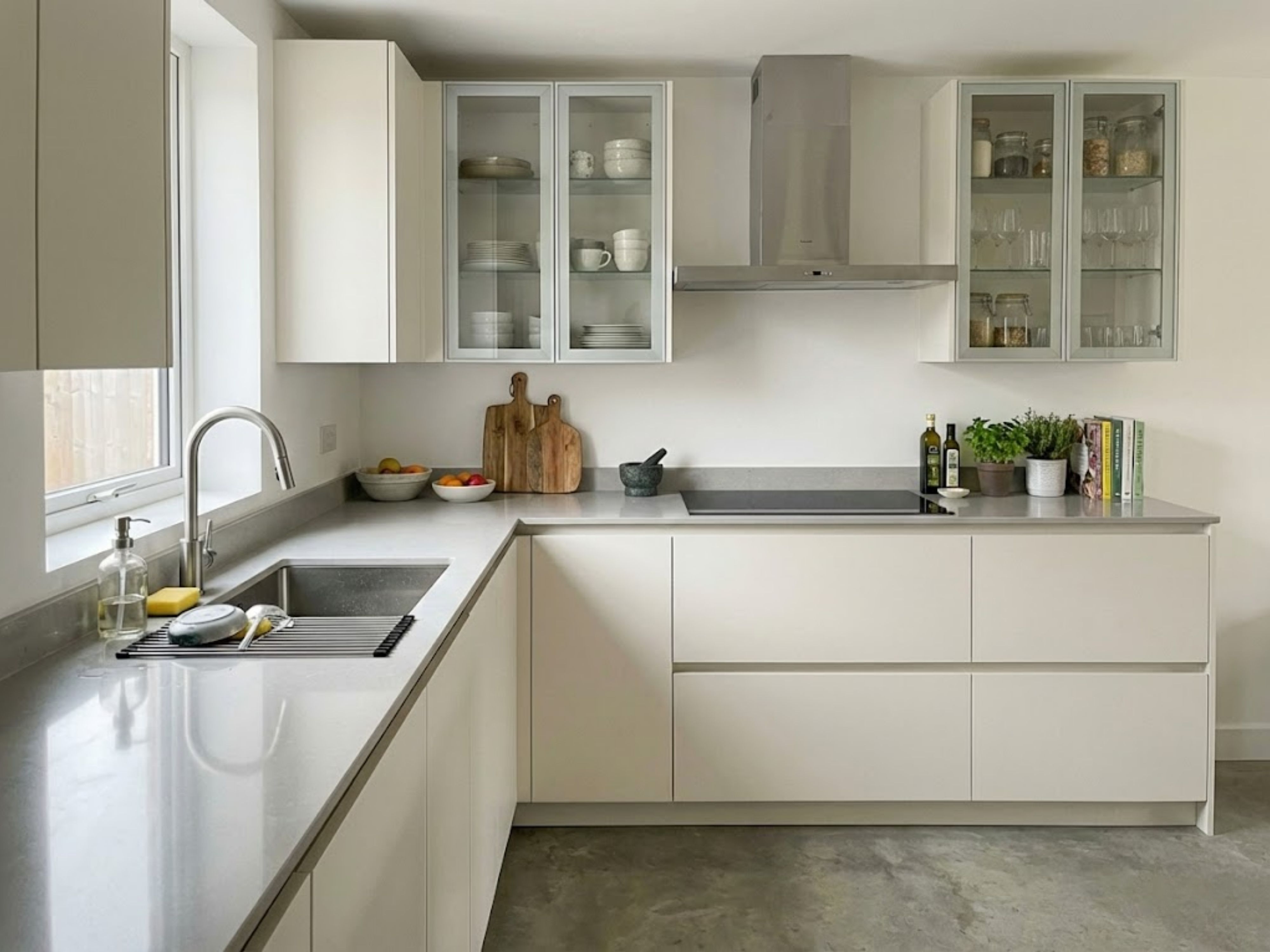 Modern L-shaped kitchen with white cabinets and window - Beautiful Homes