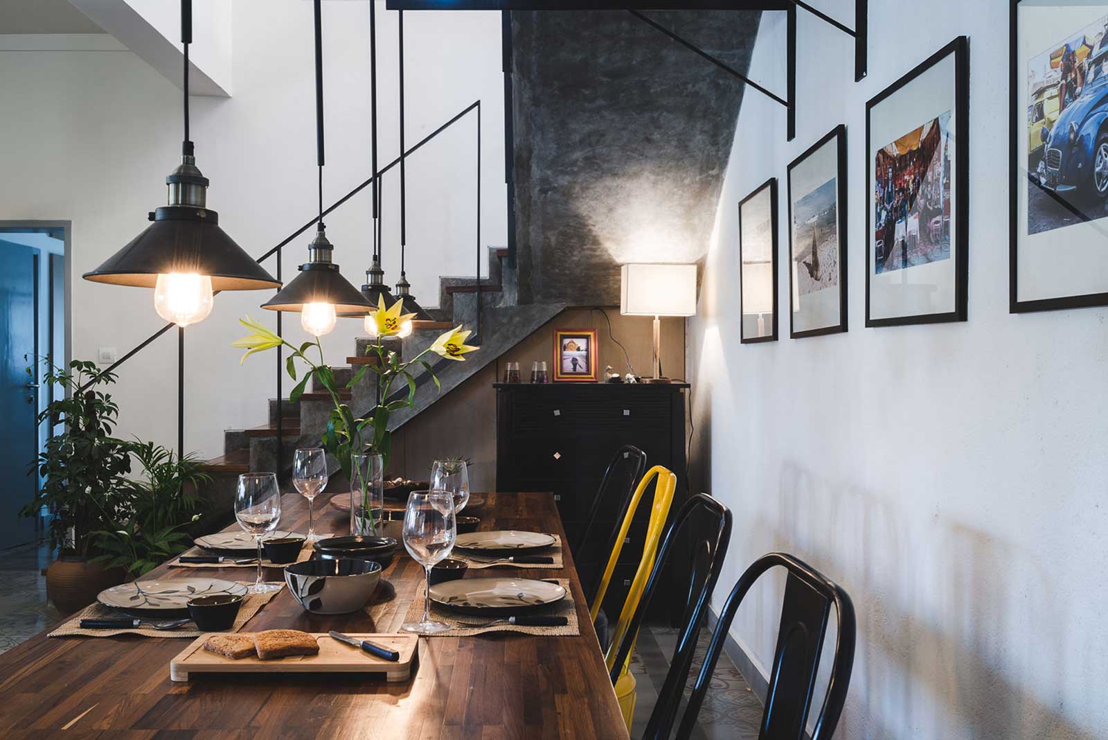 The raw cement staircase complements the industrial style furniture and lighting of the dining space - Beautiful Homes