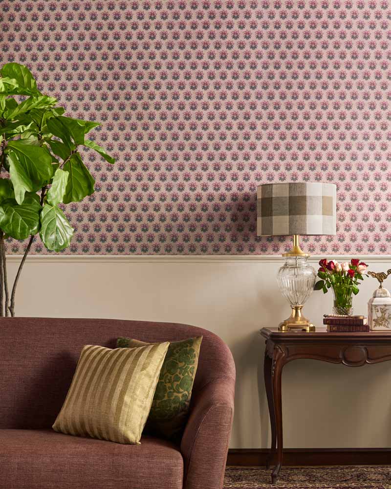 A room with a brown sofa and a pink floral wallpaper