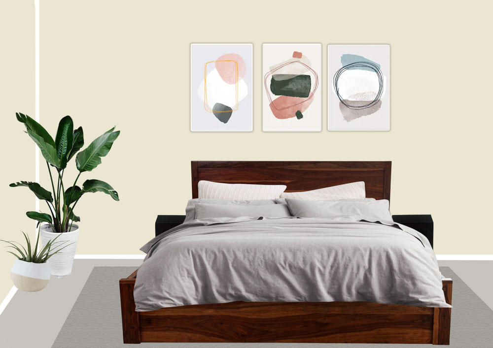 An off white bedroom with three art prints on the wall behind and a couple of planters in one corner