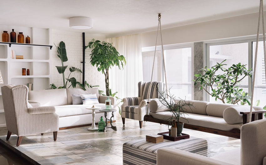 A living room with a white sofa set and plants