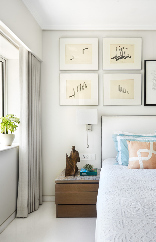 A white bedroom with framed artwork hung behind the bed