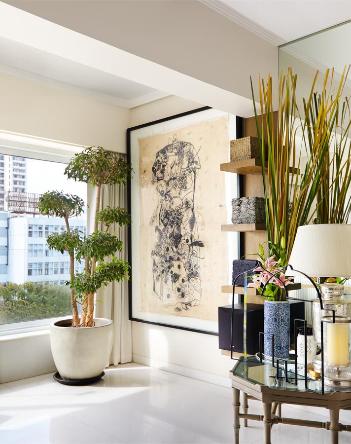 A large artwork framed on the wall next to a planter
