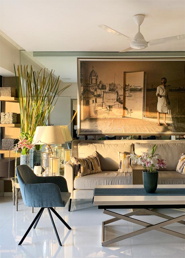 Living room with a white sofa, a  blue chair and  a large artwork on the wall behind the sofa