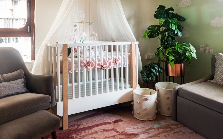 A white wooden cot with 'Sophia' written on it and beside it is a planter