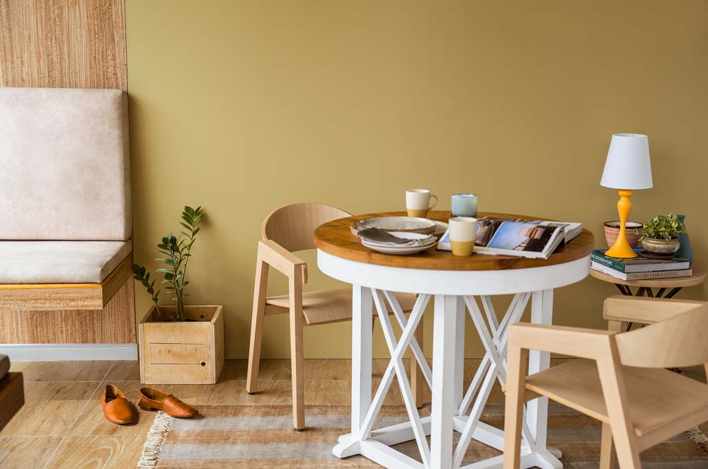 A seating area with a circular wooden table, two chairs and a rug