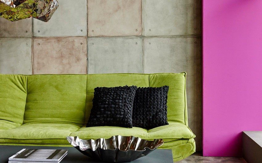 Living room with a green sofa, black cushions, textured walls and a grey coffee table