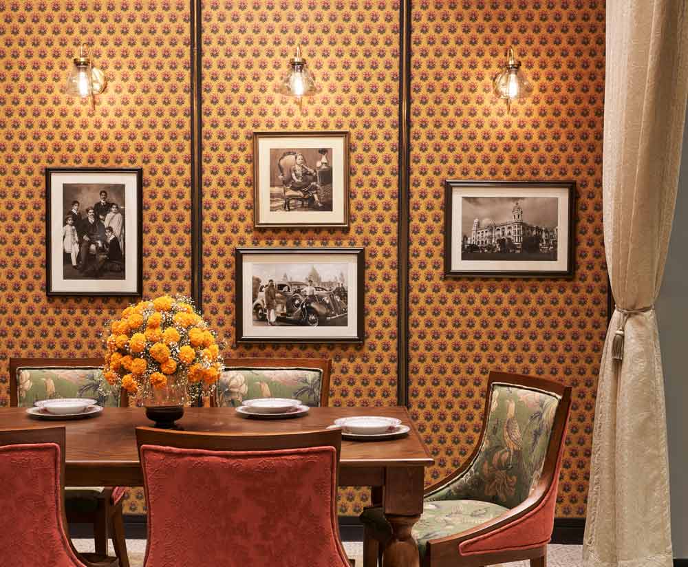 A dining room with an orange wallpaper and artworks with accent lights
