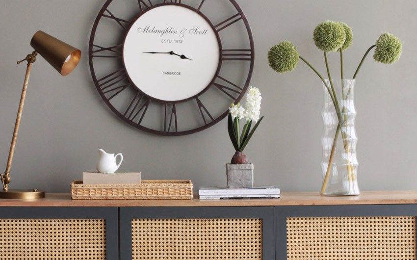 A lamp placed on a rattan console along with a flower vase and a small planter