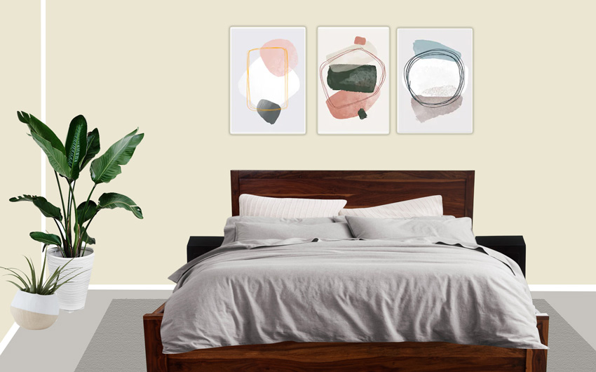 An off white bedroom with three art prints on the wall behind and three planters in one corner
