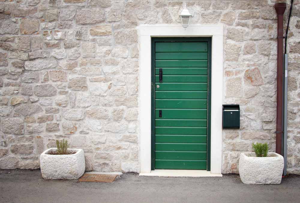Nature inspired leafy green coloured front door with stone façade rustic exterior - Beautiful Homes