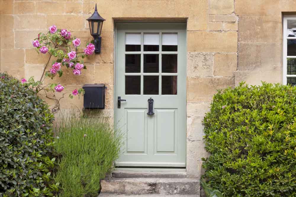 Moss green coloured glass and wood front door with pale yellow exterior - Beautiful Homes
