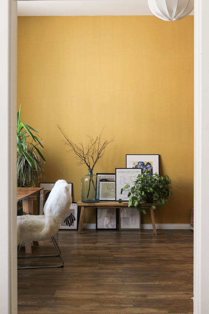 A yellow room with frames placed on the floor