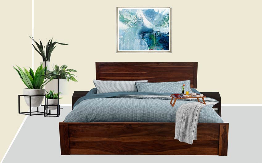 A wooden bed in a off white coloured room with three planters in one corner and a blue bedcover