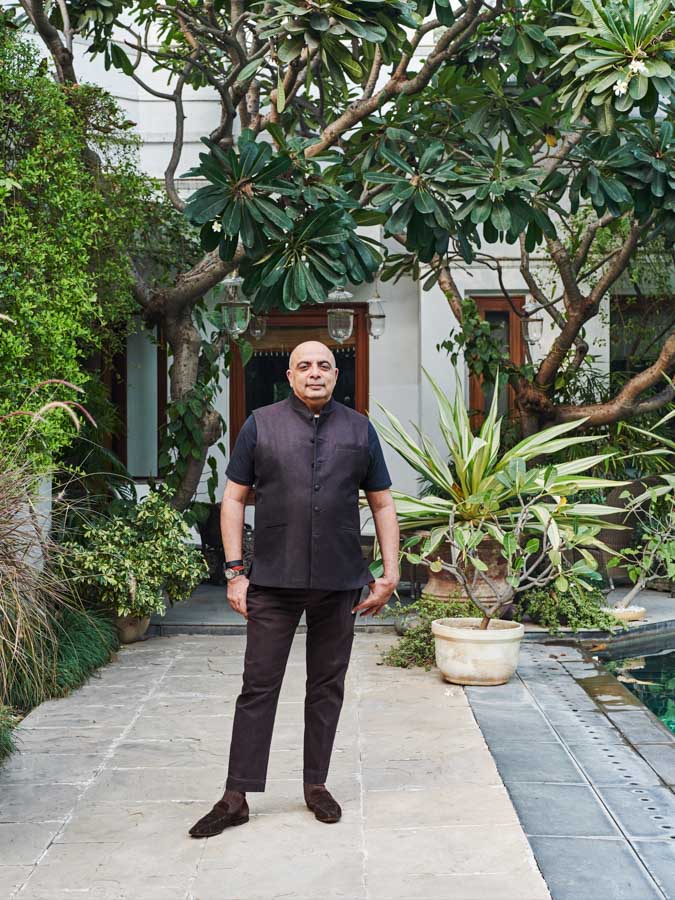 Designer Tarun Tahiliani standing outside his house in Delhi with trees and plants around him - Beautiful Homes